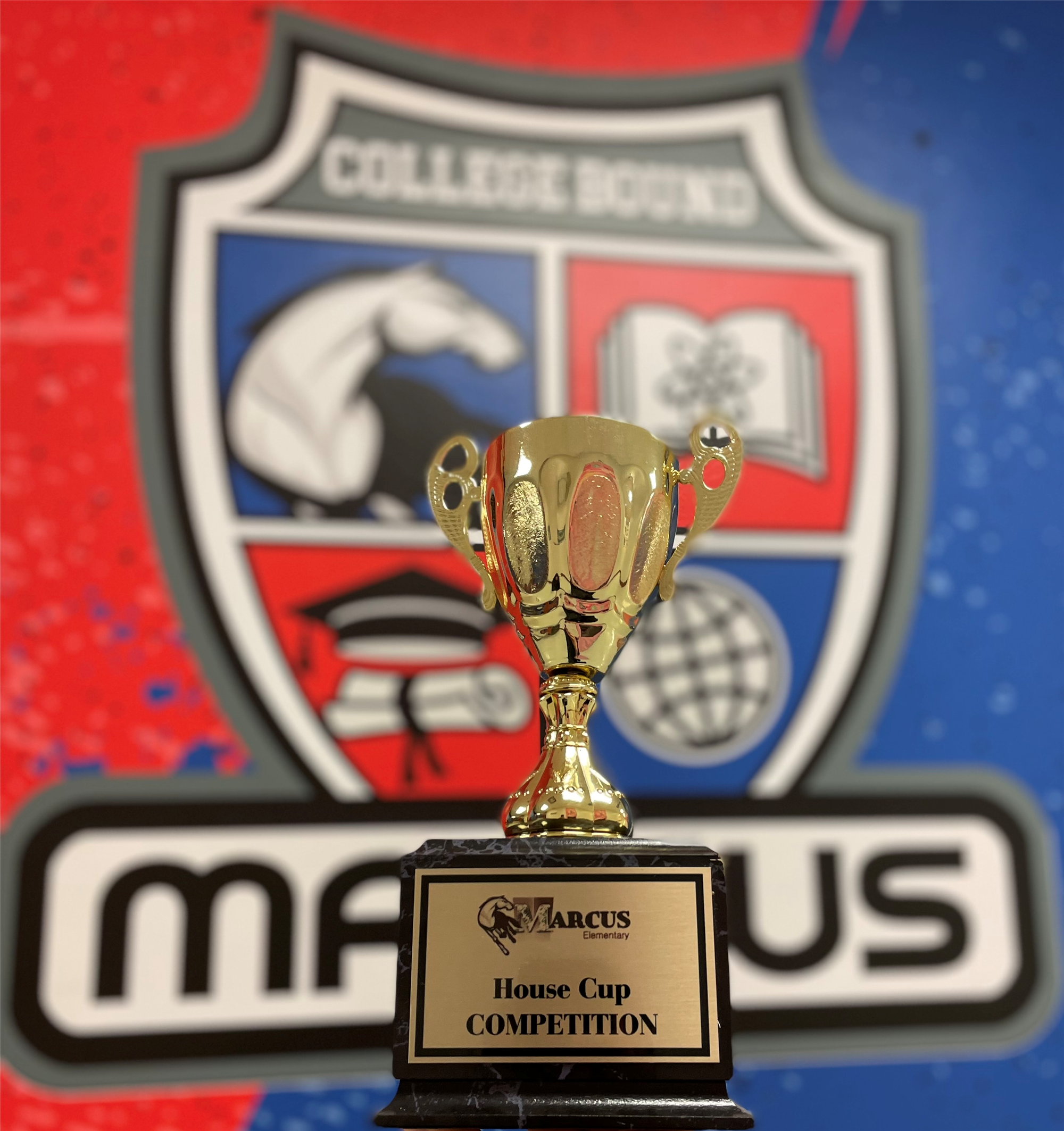 A closeup shot of the House Cup trophy with the Marcus crest in the background